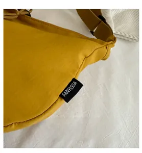 Close-up of bright yellow nylon fabric texture and branded woven label on the shoulder bag