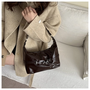 Dettaglio della borsa in pelle lucida marrone scuro abbinata a un cappotto in lana