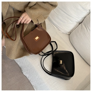 Close-up of glossy patent leather bucket bags with gold hardware on a white sofa