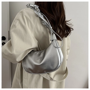 Close-up of a silver crescent underarm bag with a scrunchie shoulder strap on a model