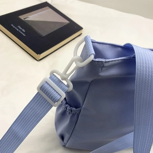 Detail view of light blue academic style crossbody bag with white adjustable strap hooks