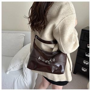 Detail of dark brown polished faux leather shoulder bag with silver buckle and belt eyelets