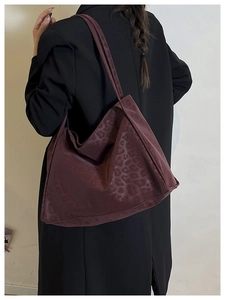 Close-up of a burgundy leopard print tote bag with high-quality suede texture on a model
