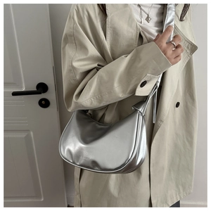 Silver crescent underarm bag with metal finish and Fashion & Bags text on beige trench coat