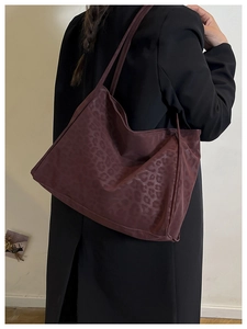 Detail of burgundy tote bag showing glossy leopard pattern texture and slim shoulder straps