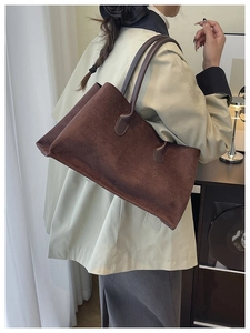 Macro view of dark brown suede tote bag texture with minimalist shoulder strap design