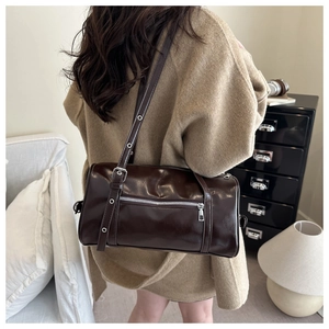 Detail view of retro dark brown cylinder shoulder bag with silver hardware on model