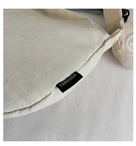 Detailed macro view of the cream-colored fabric tote with a black FANYISSA woven label