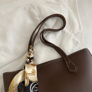 Dark brown faux leather tote bag with white contrast stitching and patterned silk scarf