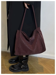 Close-up of deep burgundy suede tote bag with subtle leopard pattern and long straps