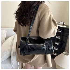Detail of adjustable strap and glossy black patent leather finish on the shoulder bag