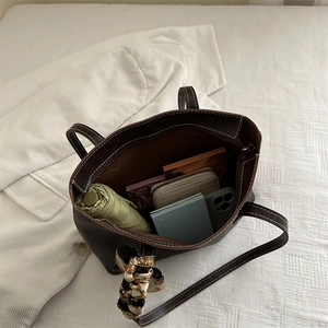 Grand sac cabas marron foncé avec surpiqûres et foulard en soie, présenté avec des objets