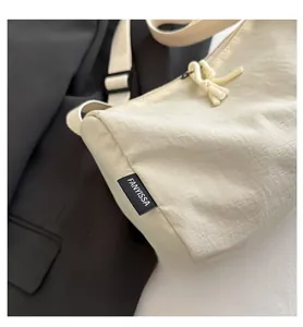 Close-up of beige nylon pillow bag featuring a woven brand label and zip cord detail