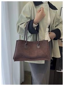 Detailed texture of a brown suede tote bag with minimalist cylindrical handles for work
