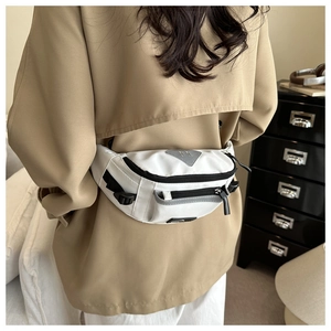 Close-up of white saddle bag with black contrast zippers and reflective triangle detail