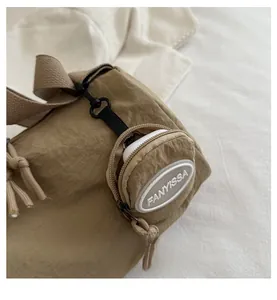 Detail of tan nylon bag with pleated texture and mini pouch storing wireless earbuds