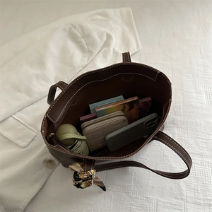 Deep brown leather tote bag with white stitching and silk scarf accessory