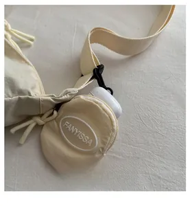 Detail of nylon crescent bag with a small round pouch holding wireless earbuds