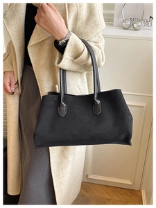 Detail shot of black faux suede tote bag with slim leather handles and matte finish