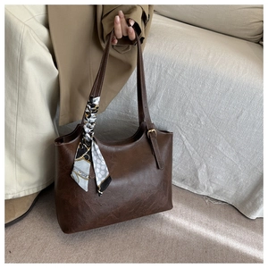 Gros plan sur le sac cabas vintage en cuir marron avec un foulard en soie décoratif