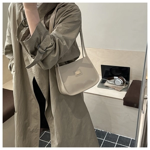 Minimalist beige PU leather shoulder bag with gold logo plaque shown in a lifestyle setting