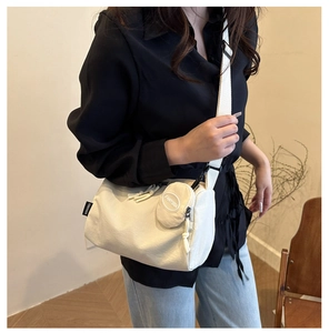 Close-up of off-white canvas crossbody bag with round coin purse and nylon strap