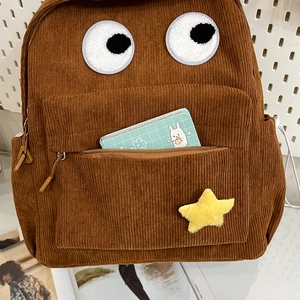 Brown corduroy backpack with cartoon eye embroidery and a yellow star plush charm