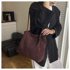 Close-up of matte burgundy tote bag with gold logo and thick braided handle texture