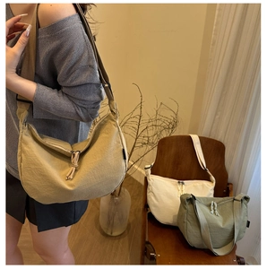 Three minimalist canvas dumpling bags in khaki, off-white, and olive green with tassel details