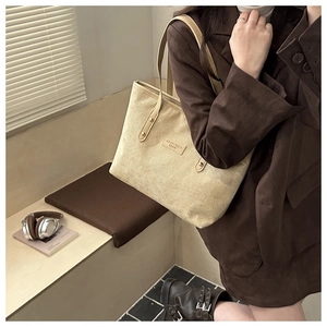 Detail of beige corduroy tote bag with leather logo patch and soft fabric texture