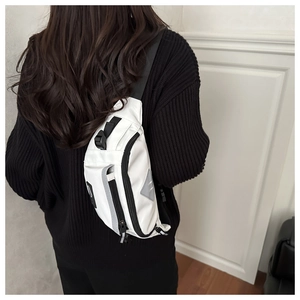 Close-up of white crossbody bag featuring black adjustable straps and multi-zipper detail