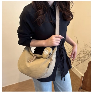 Détail du sac hobo en toile beige avec un mini porte-monnaie rond amovible sur la bandoulière