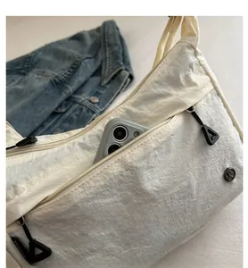 Dettaglio della borsa a tracolla in nylon crema con doppia tasca zip e vano portacellulare