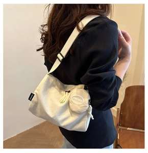 Detail of cream canvas crossbody bag with small round coin purse and adjustable strap