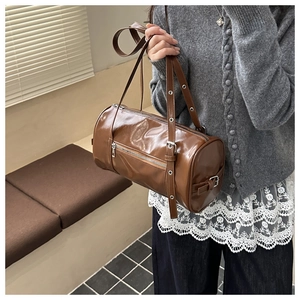 Macro detail of brown leather Boston bag featuring adjustable strap and silver metal eyelets