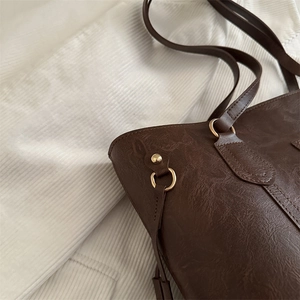 Vintage dark brown large tote bag with leather texture and gold hardware on white fabric
