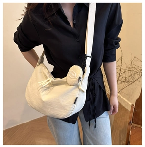 Détail du sac bandoulière croissant crème minimaliste avec son petit porte-monnaie assorti