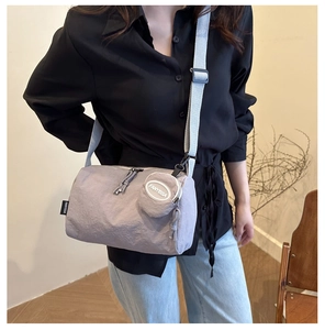 Detail of lavender nylon cylinder crossbody bag with a round mini pouch and wide strap