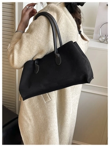 Side view of a black minimalist tote bag showing the matte texture and shoulder fit