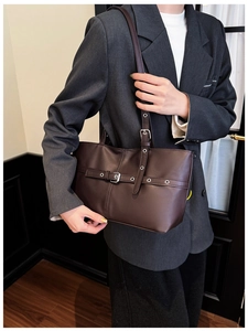Detail of vintage brown leather tote featuring stylish silver metal buckles and eyelets