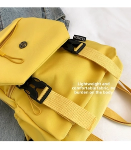 Detail of yellow nylon backpack featuring black plastic buckle and adjustable straps