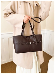 Detail of dark brown faux leather tote bag featuring decorative belt and metal buckle strap