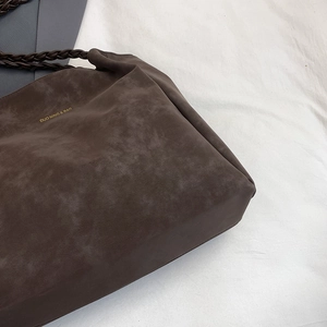 Minimalist dark brown matte tote bag with woven handles and gold lettering brand detail