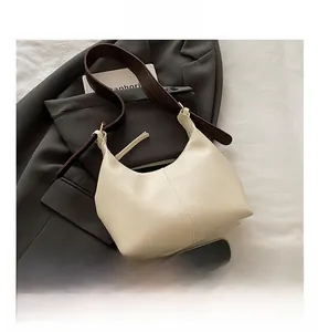 Detail of cream shoulder bag featuring fine leather texture and contrasting brown strap