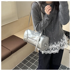 Silver metallic cylinder shoulder bag styled with a grey sweater in a lifestyle setting