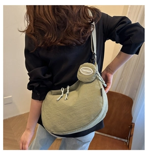 Détail du sac bandoulière en nylon vert avec une petite pochette ronde amovible