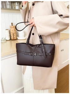 Detail of dark brown leather tote bag with metallic buckle and adjustable straps