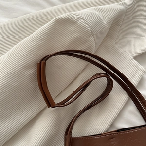 Deep brown leather bucket bag with thin double shoulder straps shown from a top-down view