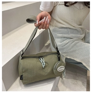 Detail of olive green nylon cylinder bag with dual zippers and a small round coin purse
