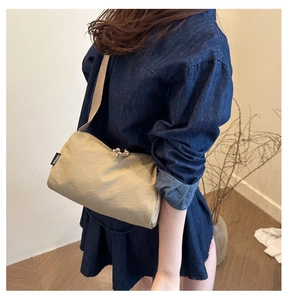 Detail of beige crossbody bag with textured fabric and branded Favyissa tag label